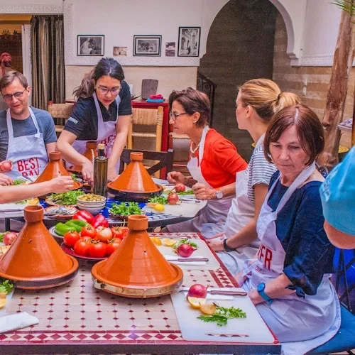 Participants preparing food with vegetables and clay tagines in a Marrakech cooking class